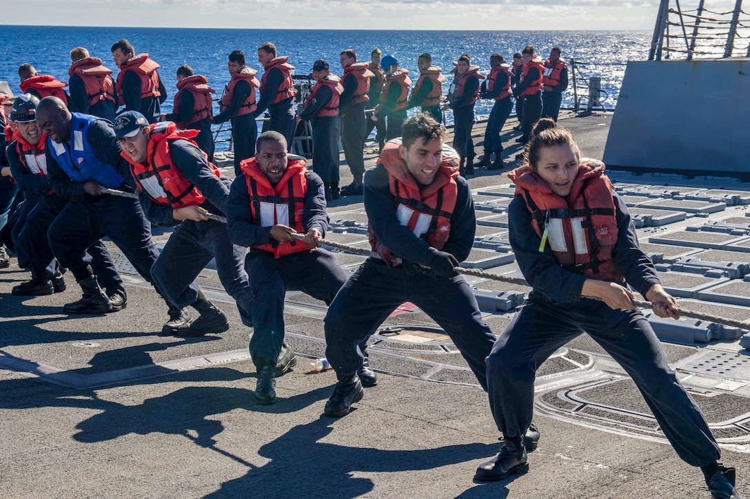A line of sailors pull a line.