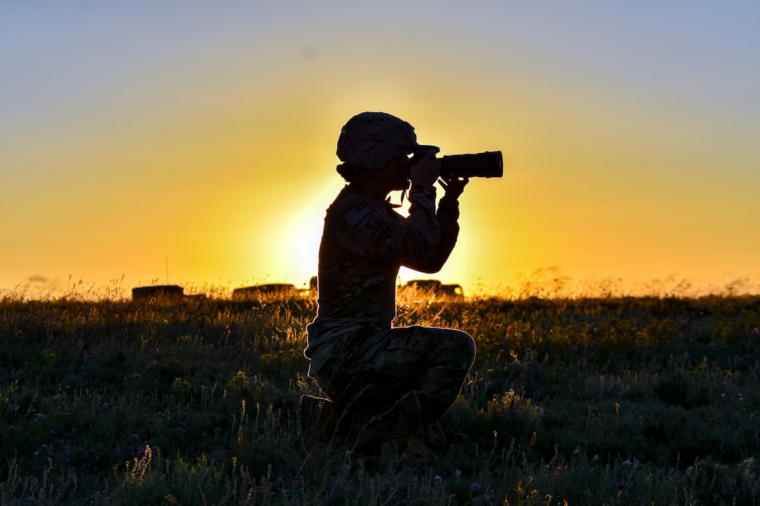 A photographer is silhouetted by the sunrise.
