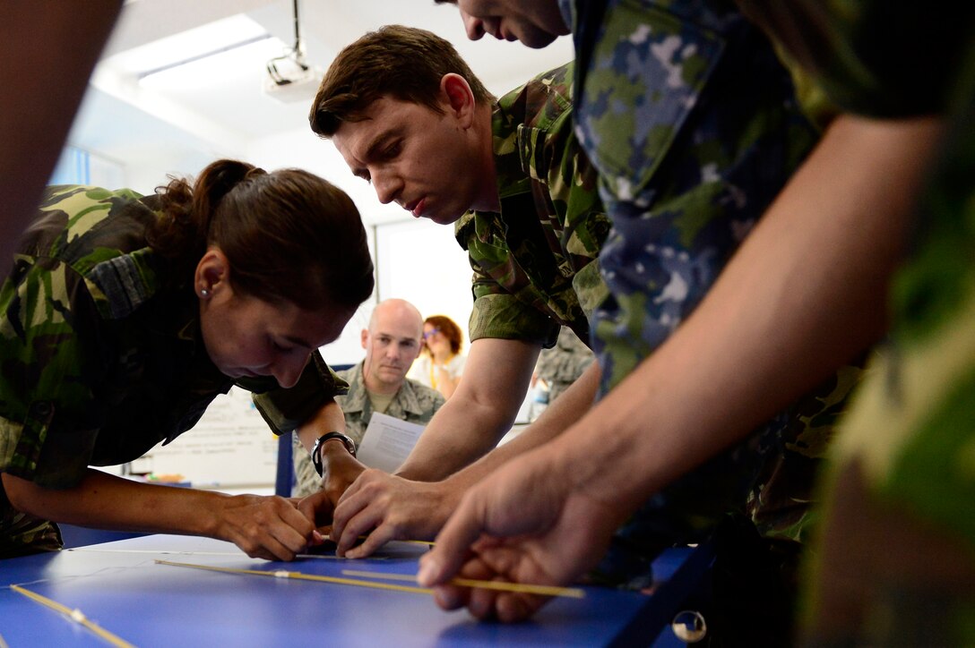 U.S. Air Force Senior Master Sgt. William Took, Senior noncommissioned officer academy instructor, watches as three Romanian Air Force students participate in a strategic thinking exercise during the first-ever senior NCO mobile education course June 8-22, 2018, at Boboc Air Base, in Buzău, Romania. The SNCOA mobile training team partnered with the Inter-European Air Forces Academy to provide a two-week course, condensed from the full five-week course held at Maxwell Air Force Base-Gunter Annex, Ala. (U.S. Air Force photo by Tech. Sgt. Staci Kasischke)