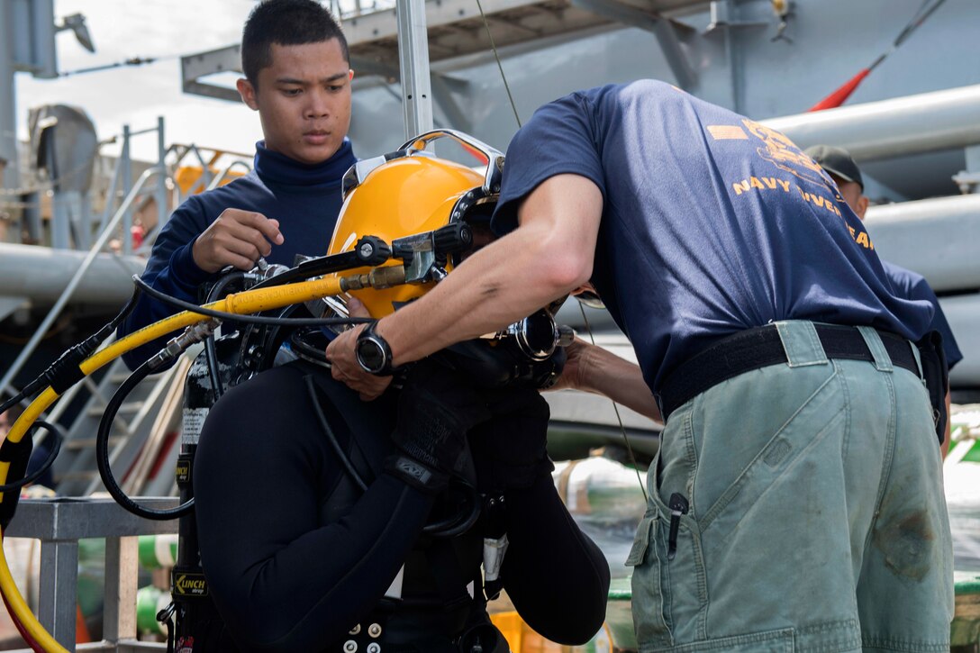 A U.S diver helps a Royal Thai diver prepare for a joint dive training encompassing supervisor drill.