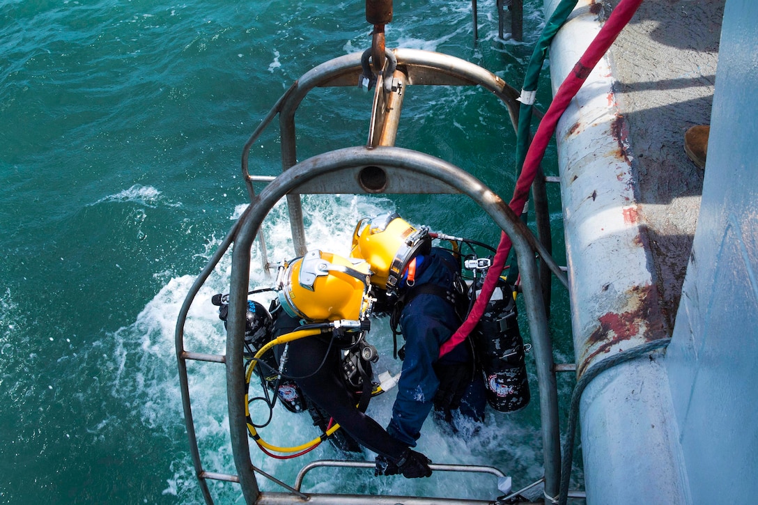 A U.S. Navy and a Royal Thai navy diver are lowered into the water to conduct a joint dive training.