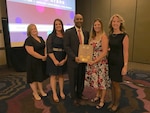 SAN DIEGO - The NSWC Crane T2 team accepts the George Linsteadt Award for Excellence in Technology Transer in San Diego. Pictured (l-r): Annie Bullock, T2 & IP Program Support, Jenna Dix, T2 Agreements Administrator, Dr. Jagadeesh Pamulapati, Office of the Secretary of Defense, Director, Labratories & STEM Development Office, Kelly Stephens, T2 Program Support & Brooke Pyne, ORTA and T2 Program Director.
