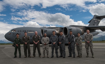 U.S. and Japan Air Self-Defense Force Airmen pose for a photo in front of a C-17 Globemaster III at Joint Base Elmendorf-Richardson, Alaska, June 19, 2018.  JASDF senior enlisted advisor Warrant Officer Masahiro Yokota (middle) toured the installation and oversaw JASDF Airmen working alongside American forces during Pacific Air Forces’ premier air combat exercise, Red Flag-Alaska, iteration 18-2.
