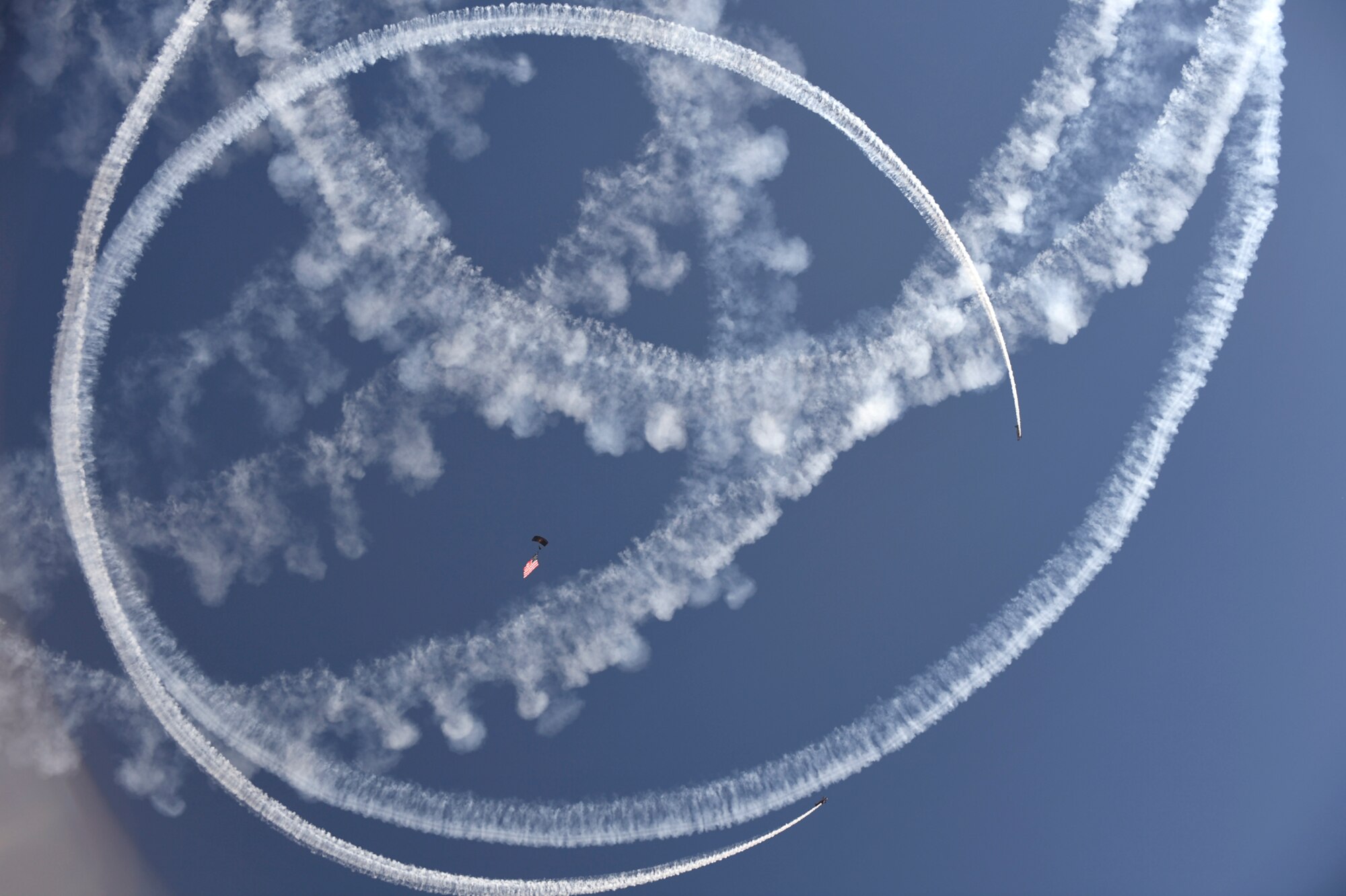 A U.S. Special Operations Command The Para-Commandos parachute demonstration team member performs a National Anthem flag jump while two aerobatic aircraft performers circle overhead during the Warriors Over the Wasatch Air and Space Show June 24, 2018, at Hill Air Force Base, Utah. The Para-Commandos are comprised of active duty special operators, such as Army Special Forces, Army Rangers, Navy SEALs, Air Force Combat Controllers and Marine Raiders. (U.S. Air Force photo by Todd Cromar)