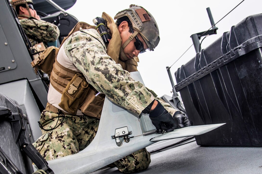 A sailor assembles an unmanned aerial vehicle before launch.