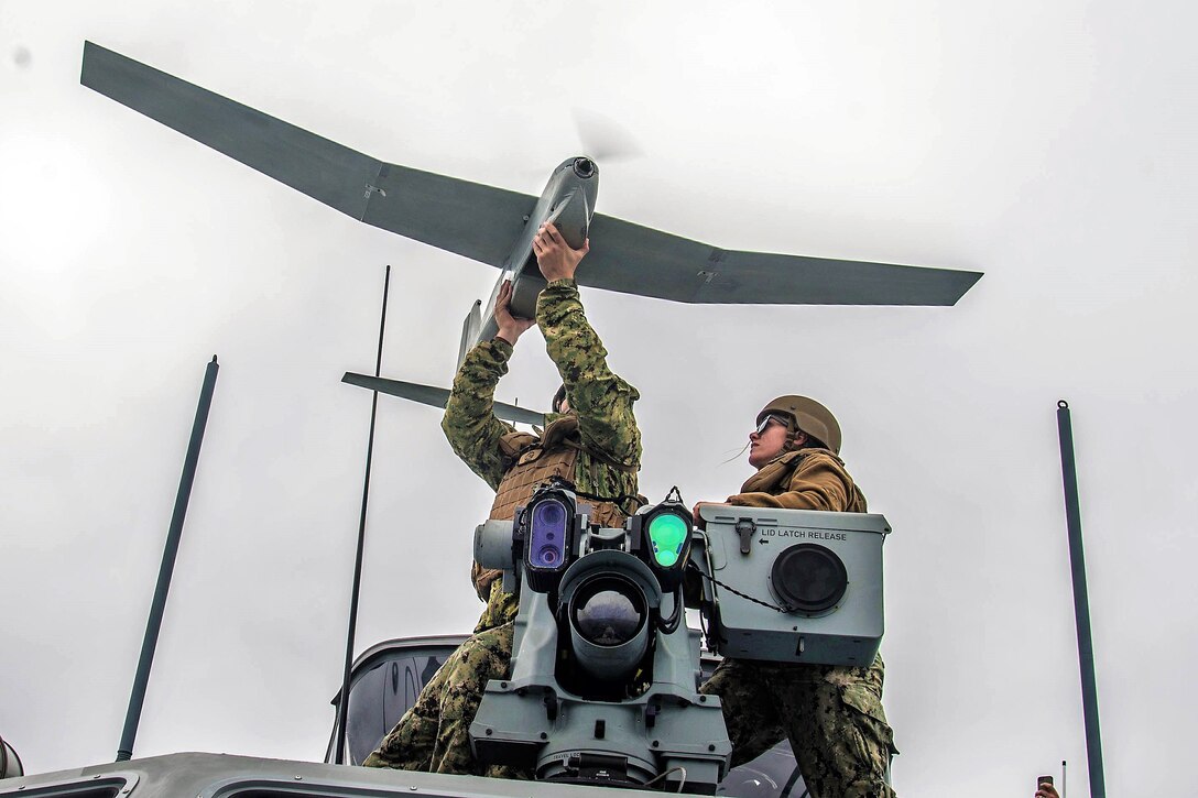 A sailor observes a team member during the launch of the unmanned aerial vehicle.