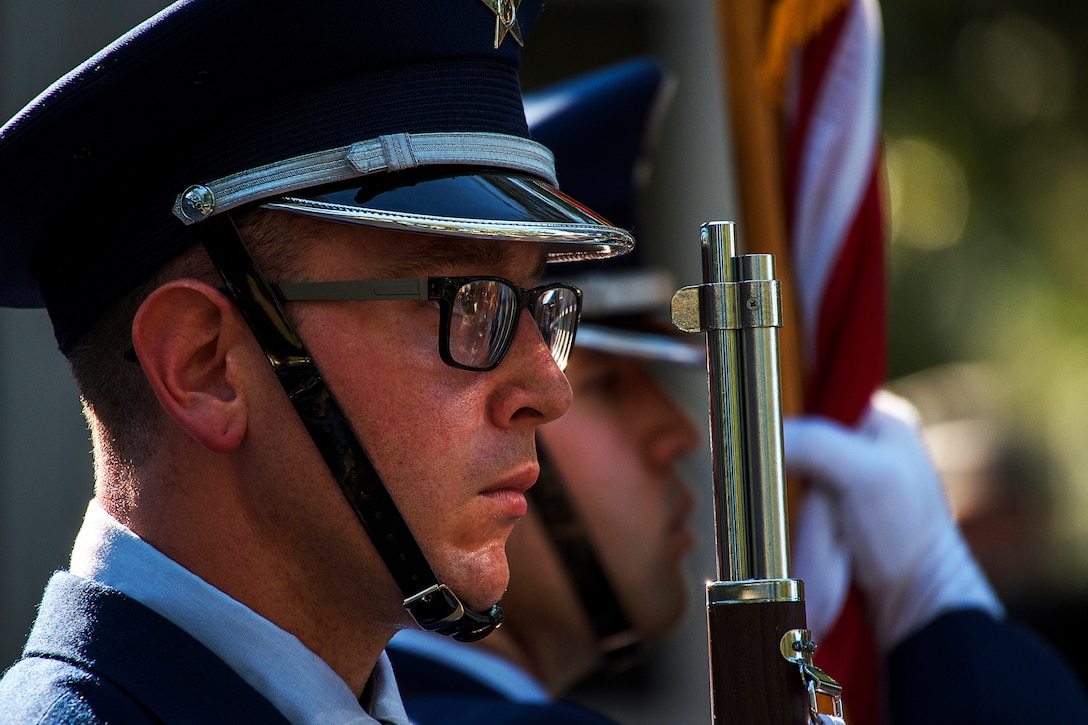 A service member stands at attention during the singing of the national anthem.