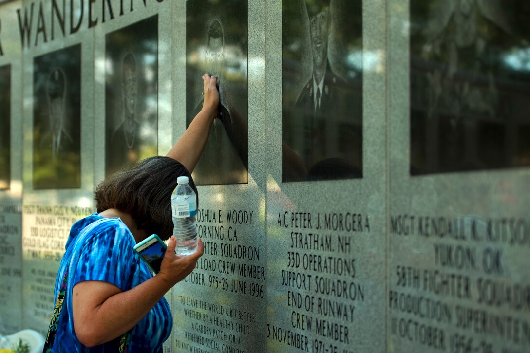 A family member places her hand on the photo of the fallen service member.