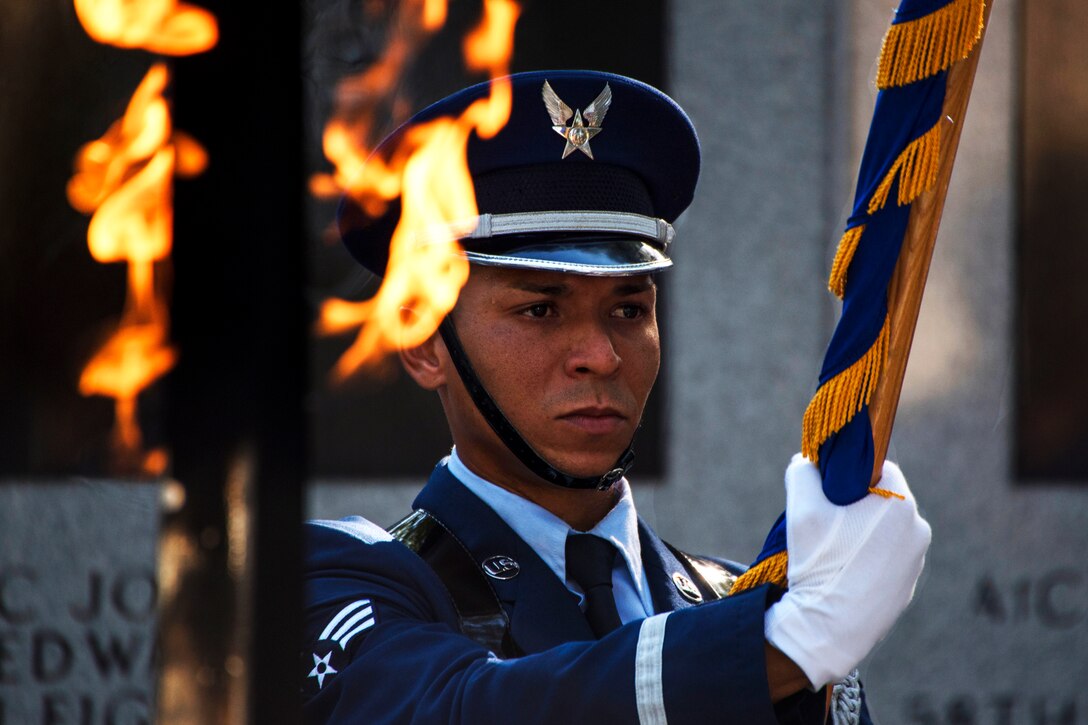 A service member present the colors at the memorial ceremony.