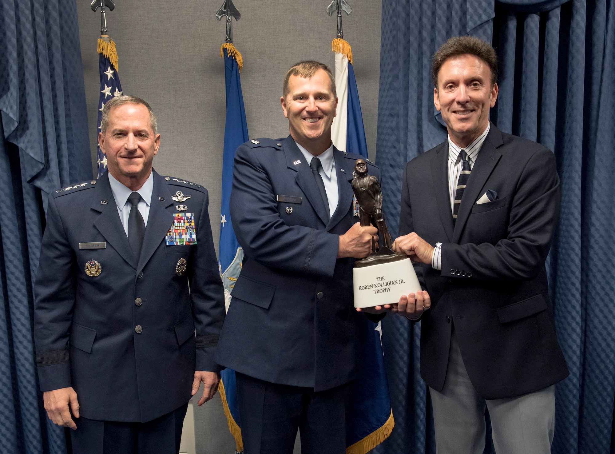 Lt. Col Daniel Finnegan receives the Koren Kolligian Trophy from Mr. Koren Kollegin II, Koren Jr.'s Nephew and Air Force Chief of Staff Gen. David L. Goldfein during a ceremony in the Pentagon,  Arlington, Va., June 25, 2018. (U.S. Air Force photo by Wayne A. Clark)