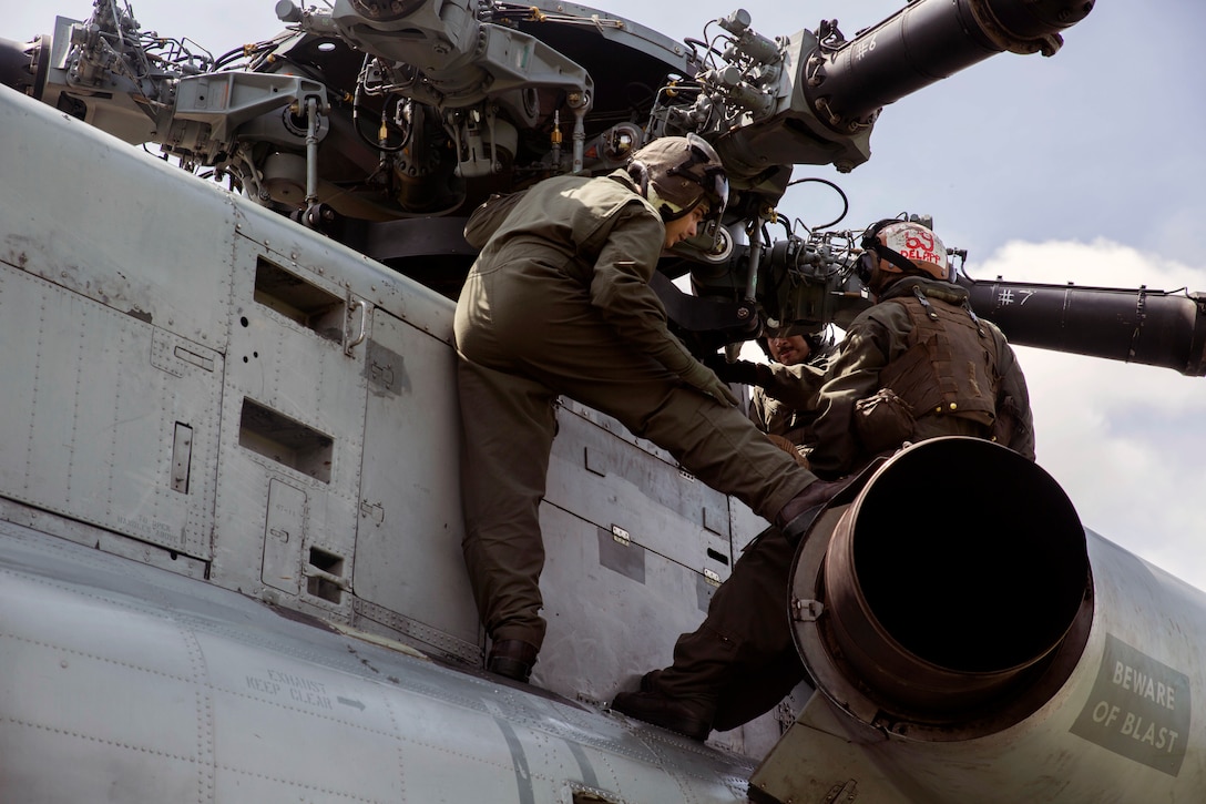Two Marines complete a maintenance check on a CH-53E Super Stallion helicopter.