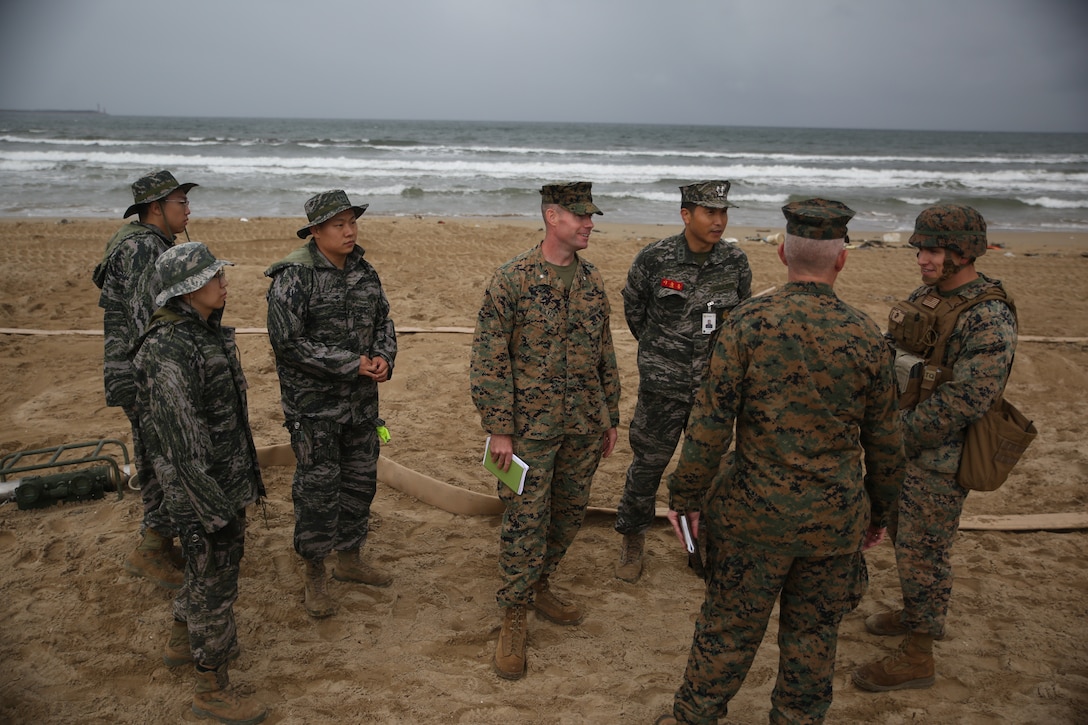 Republic of Korea Marine Corps Lt. Col. Seung-Hoon Lee, center right, commanding officer of Landing Support Battalion, ROK Marine Logistics Group, speaks with U.S. Marine Corps leadership from 3d MLG at Dogu Beach, Pohang, South Korea Oct. 19, 2017. U.S. Marine Corps Brig. Gen Daniel B. Conley, second from the right, commanding general of 3d MLG, III Marine Expeditionary Force, and Lt. Col. Matthew Mulvey, center, commanding officer of 3rd Transportation Support Battalion, CLR-3, visited the site with Lee to observe bilateral logistics training with U.S. Marines from 9th Engineer Support Battalion, 3d MLG and ROK Marines from ROKMC Landing Support Battalion, 1st MLG during Winter Workhorse 17/Korean Marine Exchange Program 18.1. III MEF Marines and Sailors gain valuable operational experience through working with our professional, warfighting ROK allies.  Our combined development is an equal, two-way exchange. (U.S Marine Corps photo by Sgt. Tiffany Edwards)