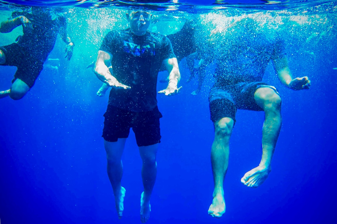 As viewed from underwater, people swim in the ocean.