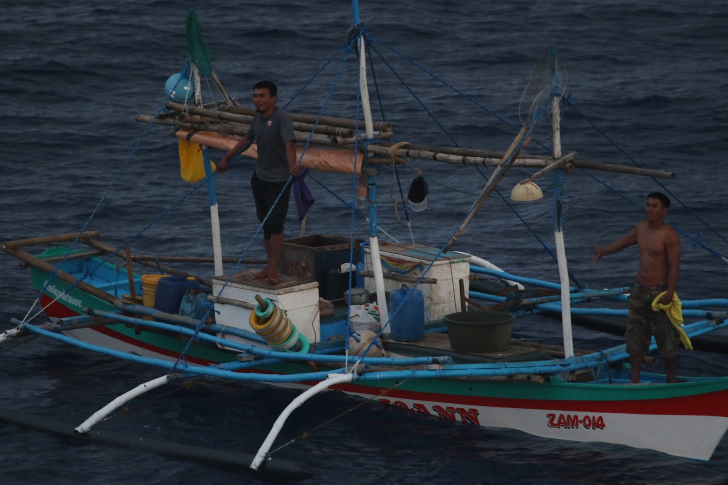 Two Filipino fishermen signal they are in distress to Sailors from USS Mustin (DDG 89) after their fishing boat was disabled in the South China Sea.  Mustin used their Rigid Hull Inflatable Boat (RHIB) to tow the adrift fishing vessel to rejoin their fellow fishermen. Mustin is forward-deployed to the U.S. 7th Fleet area of operations in support of security and stability in the Indo-Pacific region.