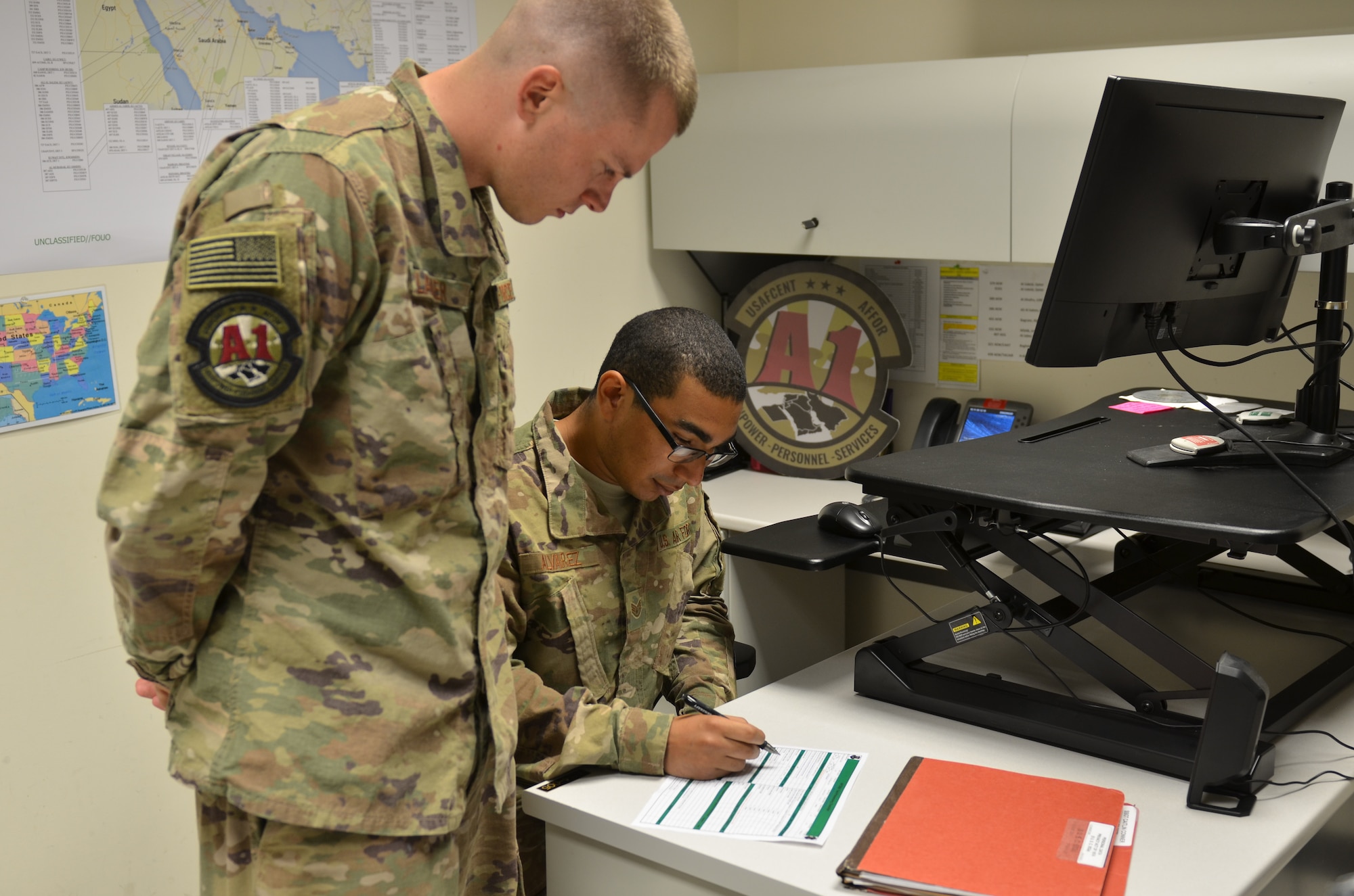 U.S. Air Force Senior Airman Joshua Glazier, U.S. Air Force Central Command deliberate and crisis action planning and execution segment operator, and U.S. Air Force Staff Sgt. Eric Alvarez, AFCENT personnel operator, review pre-deployment checklists at Al Udeid Air Base, Qatar, June 12, 2018. Manpower, Personnel and Services Directorate (A1) recently reduced the length of pre-deployment checklists in order to reduce redundancy and give more time for Airmen to spend with their families. (Photo by U.S. Air Force Staff Sgt. Caitlin Conner)