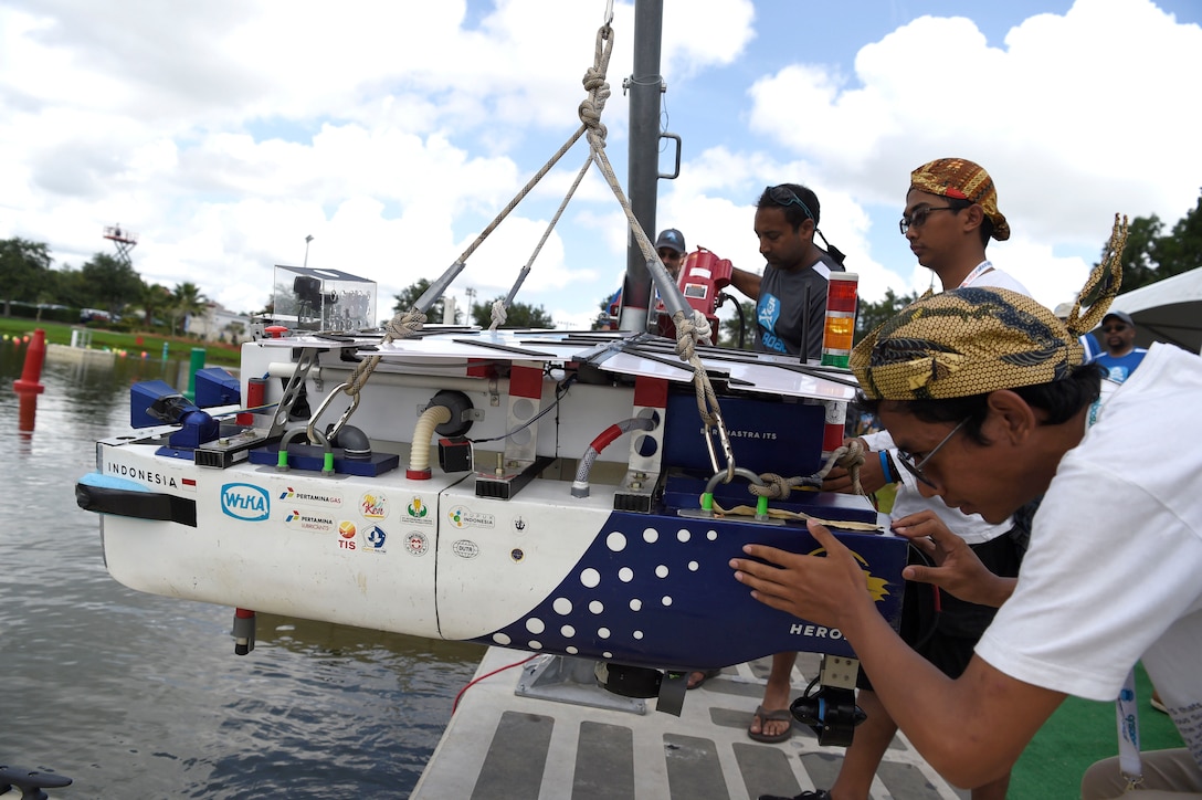 A group of kids prepare to launch an autonomous robotic boat during the finalsof an international RoboBoat Competition in Florida.