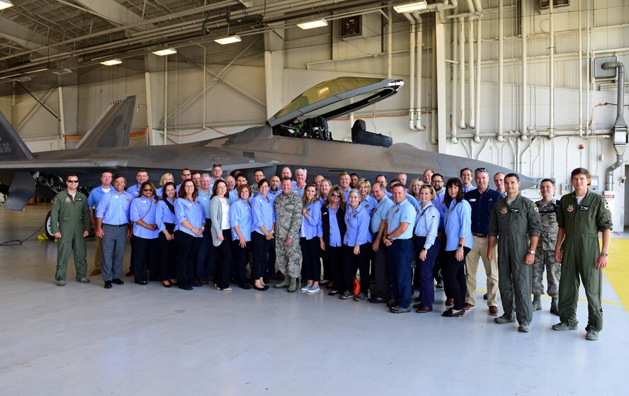 Civic leaders pose for photo in front of F-22 Raptor.