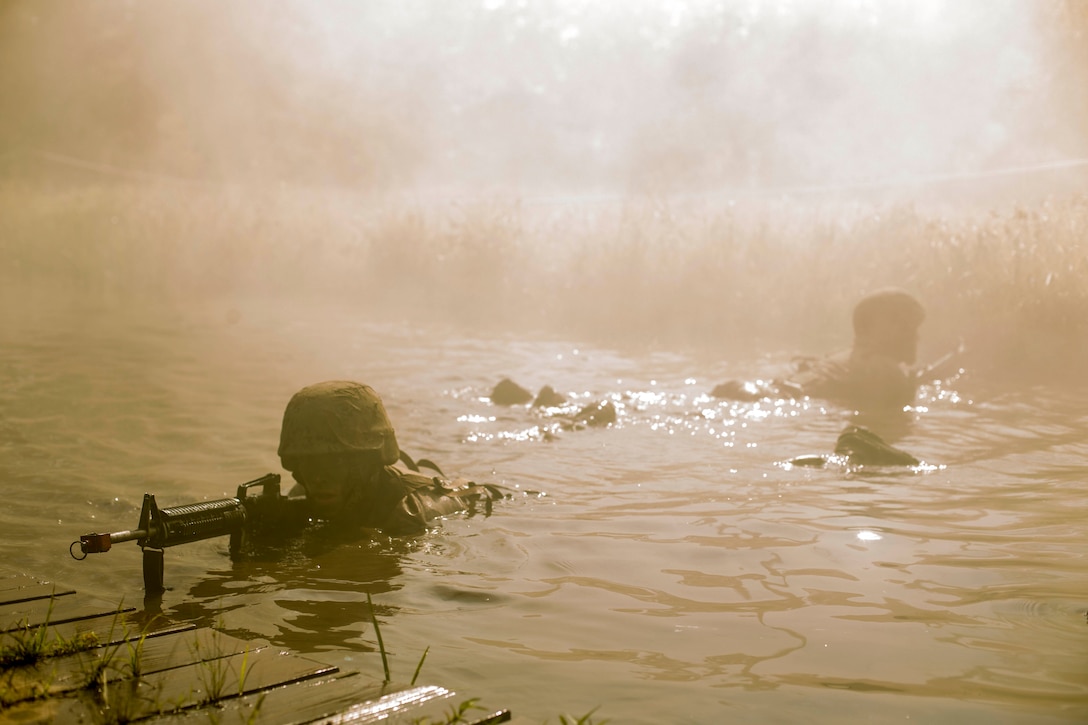 Marines lay in water with weapons.