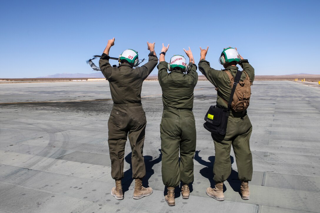 Sgt. Catherine J. Salvador (center), an avionics technician with Marine Light Attack Helicopter Squadron 775, Marine Aircraft 41, 4th Marine Division, gives a "coyote salute" with her fellow Marines as one of the squadron's AH-1W Super Cobras takes off during Integrated Training Exercise 4-18 at Marine Corps Air Ground Combat Center Twentynine Palms, California, on June 22, 2018. The "coyote salute" is a unit tradition that Marines with HMLA-775 take part in anytime their aircraft take off. (United States Marine Corps photo by Cpl. Alexis B. Rocha/released)