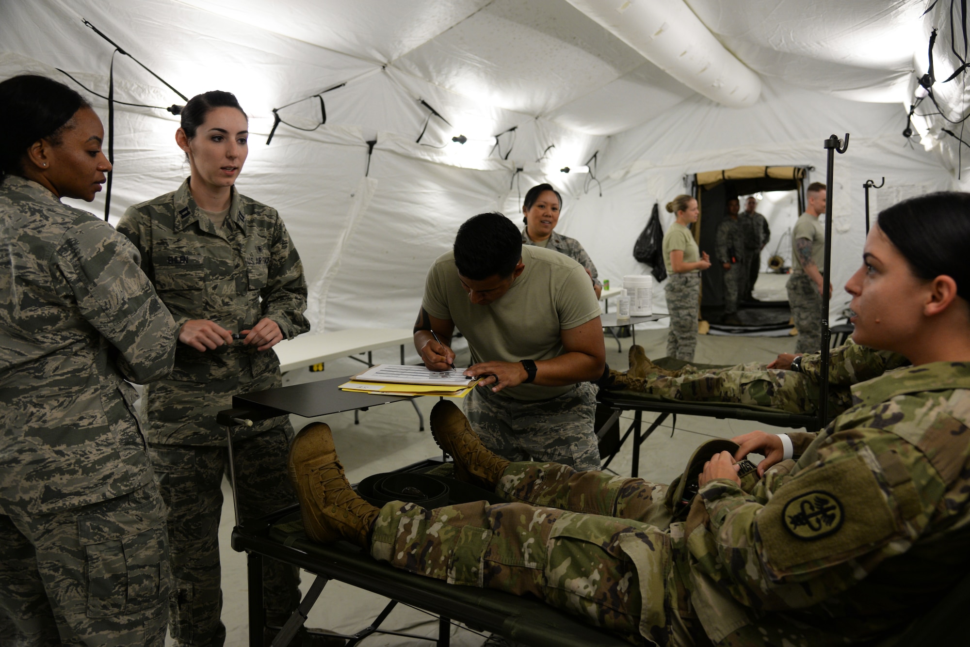 Airmen from the 86th Medical Group treat a patient with simulated minor injuries in an Expeditionary Medical Support System modular field hospital during en route patient staging training during Exercise Maroon Surge on Ramstein Air Base, Germany, June 9, 2018. Treatment at an EMEDS is a vital step in the en route care continuum, getting patients prepped for aeromedical evacuation to higher level of care. (U.S. Air Force photo by Airman 1st Class Ariel Leighty)