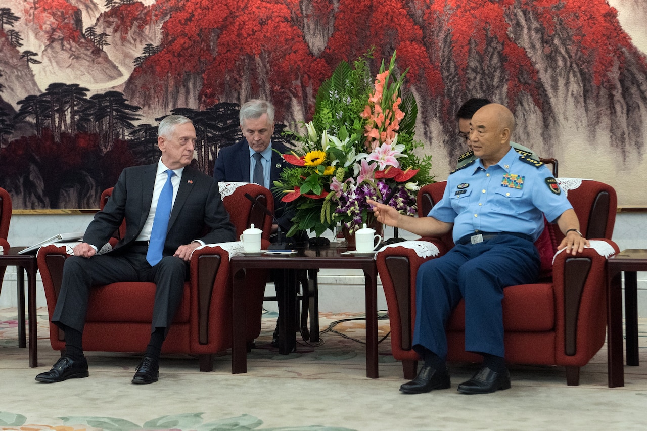 Defense Secretary James N. Mattis and a Chinese military officer sit in chairs and talk.