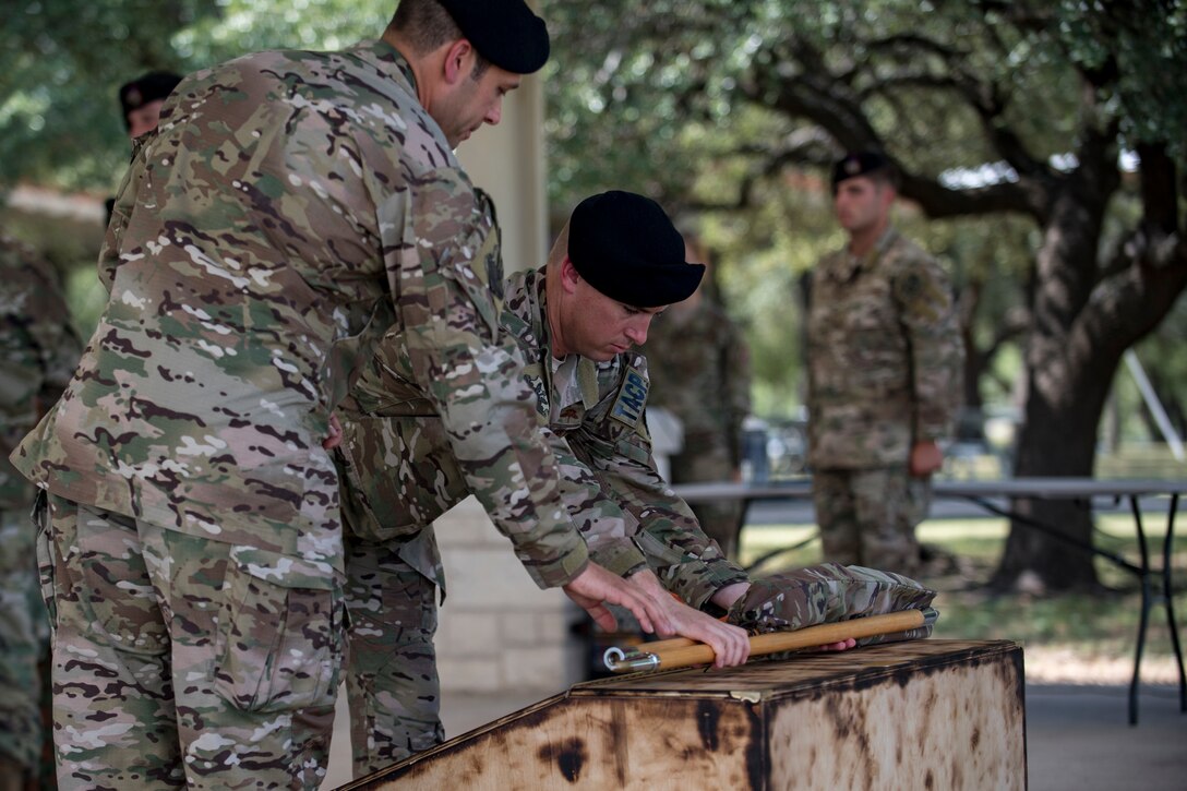 Lt. Col. Frank Biancardi, outgoing 11th Air Support Operations Squadron (ASOS) commander, and Master Sgt. Daniel Nestor, 11th ASOS superintendent, place an unassembled guidon to rest during a squadron inactivation ceremony, June 21, 2018, at Fort Hood, Texas. As a part of the 93d Air Ground Operations Wing from Moody Air Force Base, Ga., the 11th ASOS ‘Steel Eagles’ mission will remain unchanged as they continue to support Ft. Hood and absorb into the 9th ASOS. The enhanced 9th ASOS will continue to provide tactical air support to align with any U.S. Army unit that needs air support for their scheme of maneuver. (U.S. Air Force photo by Senior Airman Daniel Snider)