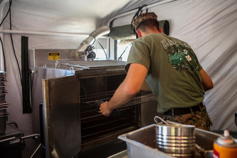 Cpl. Michael T. Moss, a food service specialist with Marine Wing Support Squadron 473, Marine Aircraft Group 41, 4th Marine Aircraft Wing, prepares a meal for the Major General W. P. T. Hill Memorial Awards competition for Food Service Excellence, during Integrated Training Exercise 4-18 at Marine Corps Air Ground Combat Center Twentynine Palms, California, on June 22, 2018. The competitive spirit fostered by the Major General W.P.T. Hill awards program contributes to improved food service excellence and increased quality of life for our Marines and Sailors. (United States Marine Corps photo by Cpl. Alexis B. Rocha/released)