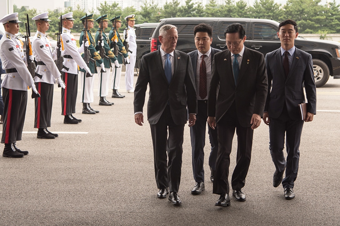 Defense Secretary James N. Mattis walks with three men.