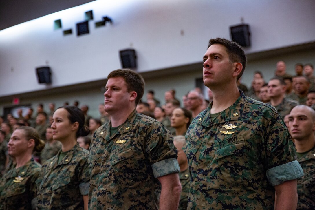 Marines, Sailors and their families stand at attention during the playing of Anchors Away by the III Marine Expeditionary Force Band during a transfer of command ceremony June 29, 2018 at Camp Foster, Okinawa Japan. Brig. Gen. Keith D. Reventlow assumed command of 3rd Marine Logistics Group during the transfer of command ceremony. Reventlow is a native of Newtown, Connecticut. (U.S. Marine Corps photo by Pfc. Terry Wong)