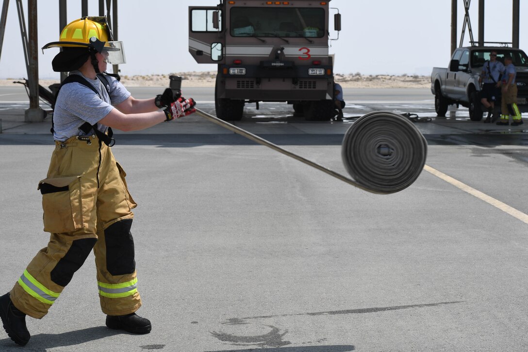 Senior Airman Rachel Johnson, 380th Civil Engineering Squadron emergency manager, rolls out a fire house during her ‘Firefighter for a Day’ training at Al Dhafra Air Base, June 25. Johnson went through several simulations throughout the day to better understand what it takes to be a firefighter. (U.S. Air Force photo by Staff Sgt. Erica Rodriguez)