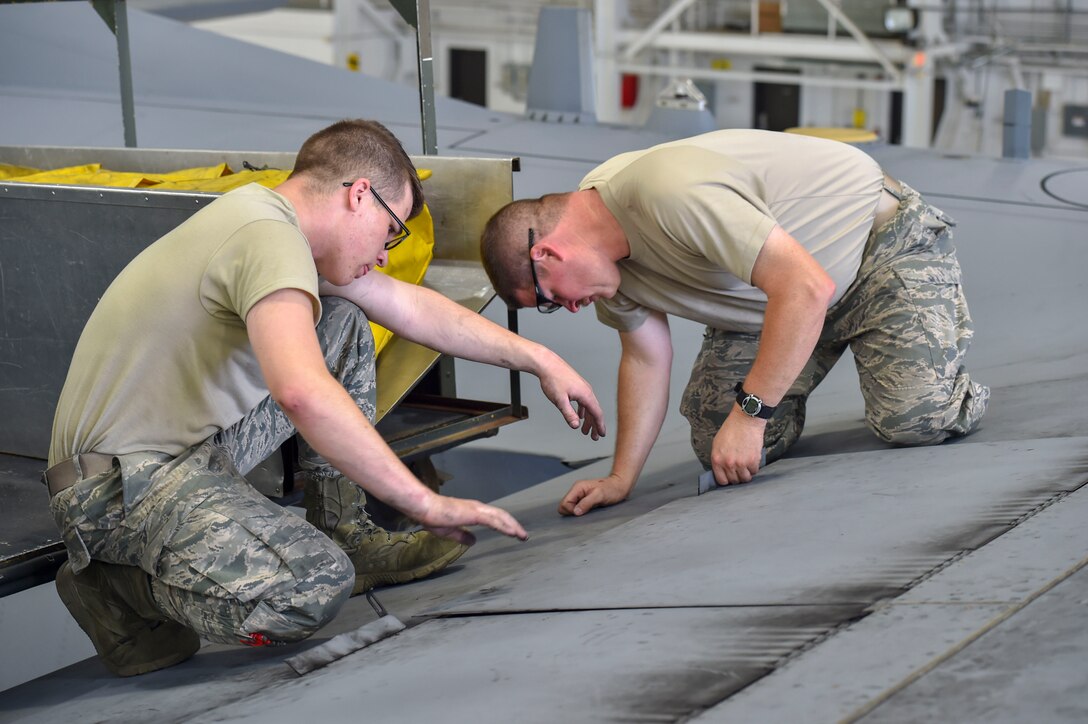 Airman Dustin Bruce and Master Sgt. Dan Scott, both aircraft maintenance technicians with the 910th Aircraft Maintenance Squadron, close a life raft compartment on the wing of a C-130H Hercules aircraft after removing the rafts here, June 13, 2018.