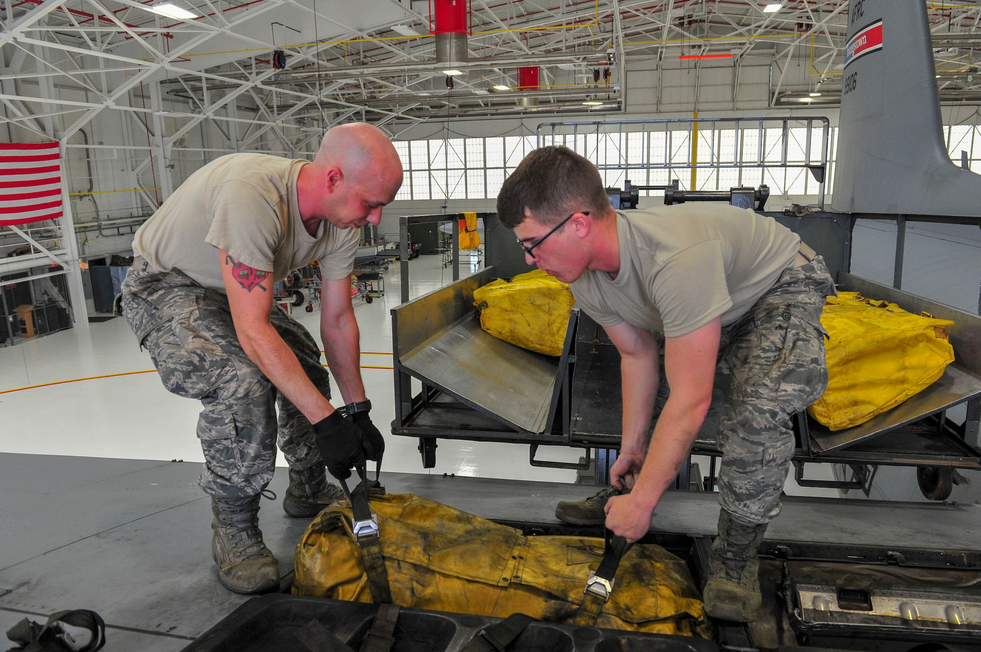 Airman Dustin Bruce and Senior Airman William Hizer, both aircraft maintenance technicians with the 910th Aircraft Maintenance Squadron, remove a 40-person life raft from a compartment on the wing of a C-130H Hercules aircraft here, June 13, 2018.