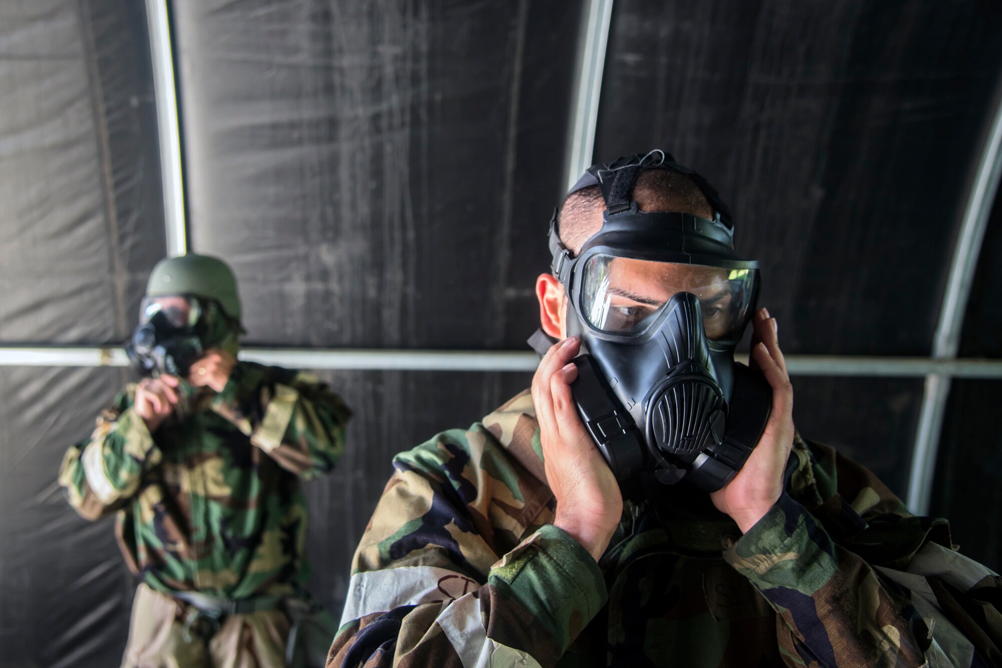 Airman 1st Class Phillip Pham, right, 23d Civil Engineer Squadron execution support specialist, performs a seal check on his gas mask during a Chemical, Biological, Radiological, Nuclear and Explosive (CBRNE) Olympics, June 21, 2018, at Moody Air Force Base, Ga. Moody held its first CBRNE Olympics to further Airmen’s overall knowledge on all of the aspects of CBRNE through a new method that was meant to establish a sense of competition and camaraderie. (U.S. Air Force photo by Airman 1st Class Eugene Oliver)