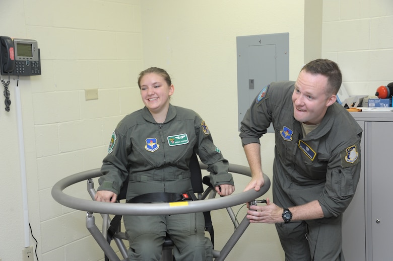 Airman 1st Class Conner Sanders, 59th Medical Wing aerospace physiology technician, prepares to spin Megan Foster on the Barany Chair during her “Pilot for a Day” orientation June 26, 2018, at Joint Base San Antonio-Randolph, Texas.  The "Pilot for a Day" program invites children of all ages, military or civilian, to be guests of the 12th Flying Training Wing and its flying squadrons for an entire day. In so doing, the 12th FTW strives to give each child a special day and a break from the challenges they may face.  (U.S. Air Force photo by Joel Martinez/Released)