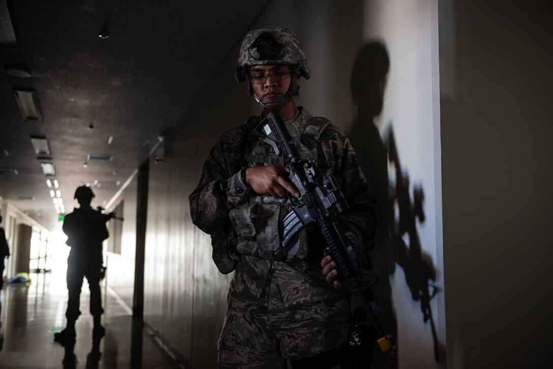 U.S. Air Force Tech. Sgt. Michael Flores, right, 18th Security Forces Squadron assistant Alpha Flight chief, and Master Sgt. Matthew Bridge, 18th SFS Alpha Flight chief, confront a simulated active shooter during a training exercise June 25, 2018, at Ryukyu Middle School, Kadena Air Base, Japan. The training enabled defenders to test new equipment, practice communication and coordination techniques. (U.S. Air Force photo by Staff Sgt. Micaiah Anthony)