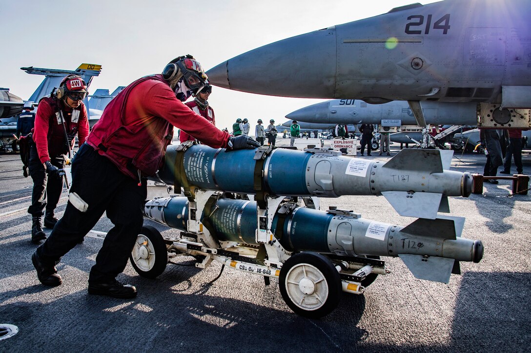 Sailors move ordnance on the flight deck of on the aircraft carrier USS Carl Vinson.