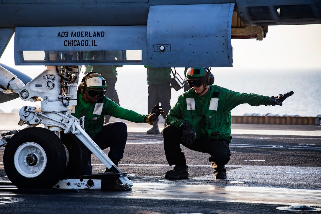 Sailors ensure an F/A-18C Hornet aircraft is correctly connected to the catapult on the flight deck of the aircraft carrier USS Carl Vinson.