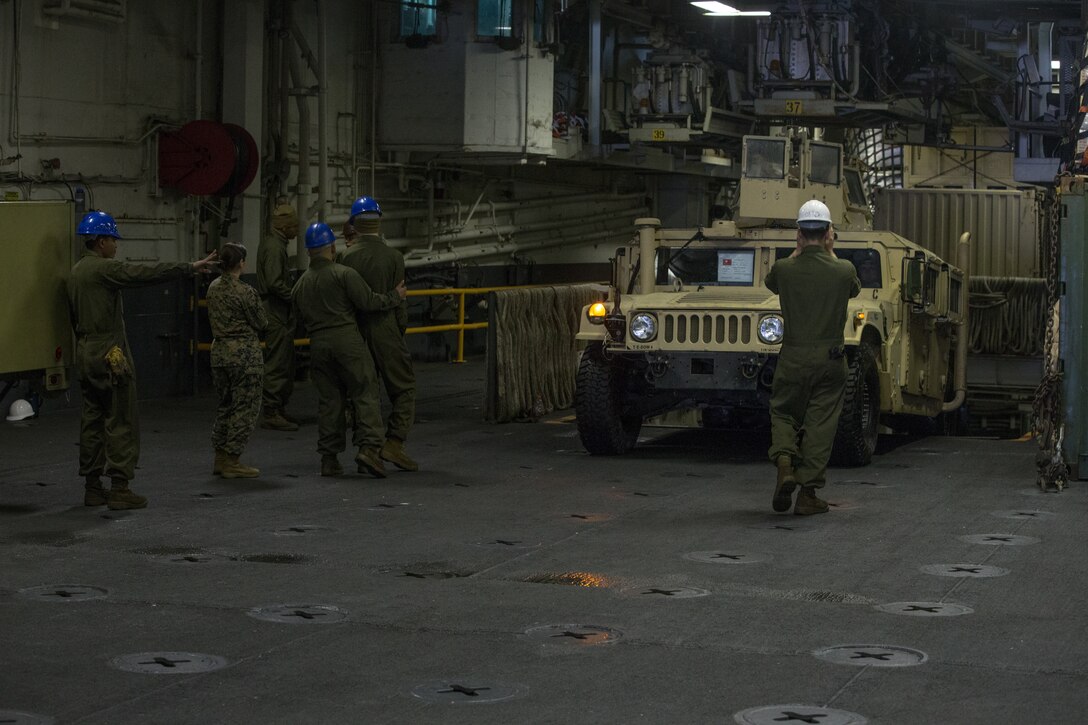 U.S. Marines with Combat Logistics Battalion (CLB) 26, 26th Marine Expeditionary Unit (MEU) provide ground guide assistance to a High-Mobility Multipurpose Wheeled Vehicle (HMMWV) down a ramp aboard the amphibious assault ship USS Iwo Jima (LHD 7), Feb. 11, 2018. The 26th MEU is deploying at sea to conduct maritime security operations, crisis response and theater security cooperation, while also providing a forward expeditionary naval presence in Europe and the Middle East. (U.S. Marine Corps photo by Cpl. Jered T. Stone)