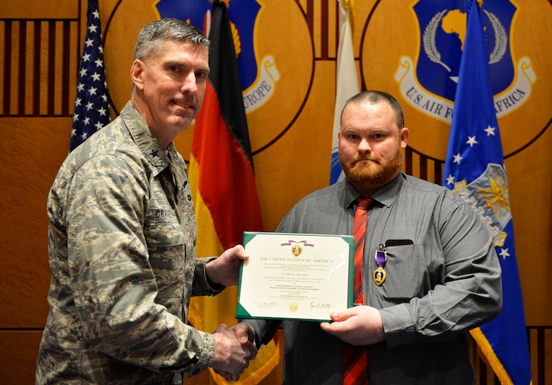 Judson Rackley, U.S. Air Forces in Europe-Air Forces Africa video operations center communications engineer, right, receives the Purple Heart from U.S. Air Force Brig. Gen. Christopher Craige, USAFE-AFAFRICA chief of staff on Ramstein Air Base, Germany, Feb. 27, 2018. The Purple Heart is awarded to veterans and military members for wounds received or death after being wounded in action against enemy forces. (U.S. Air Force photo by Senior Airman Joshua Magbanua)