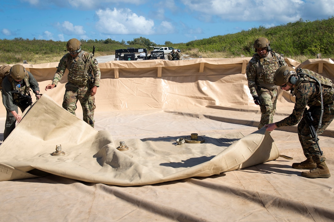 Airmen and Marines set up a helicopter expedient refueling system during an exercise.