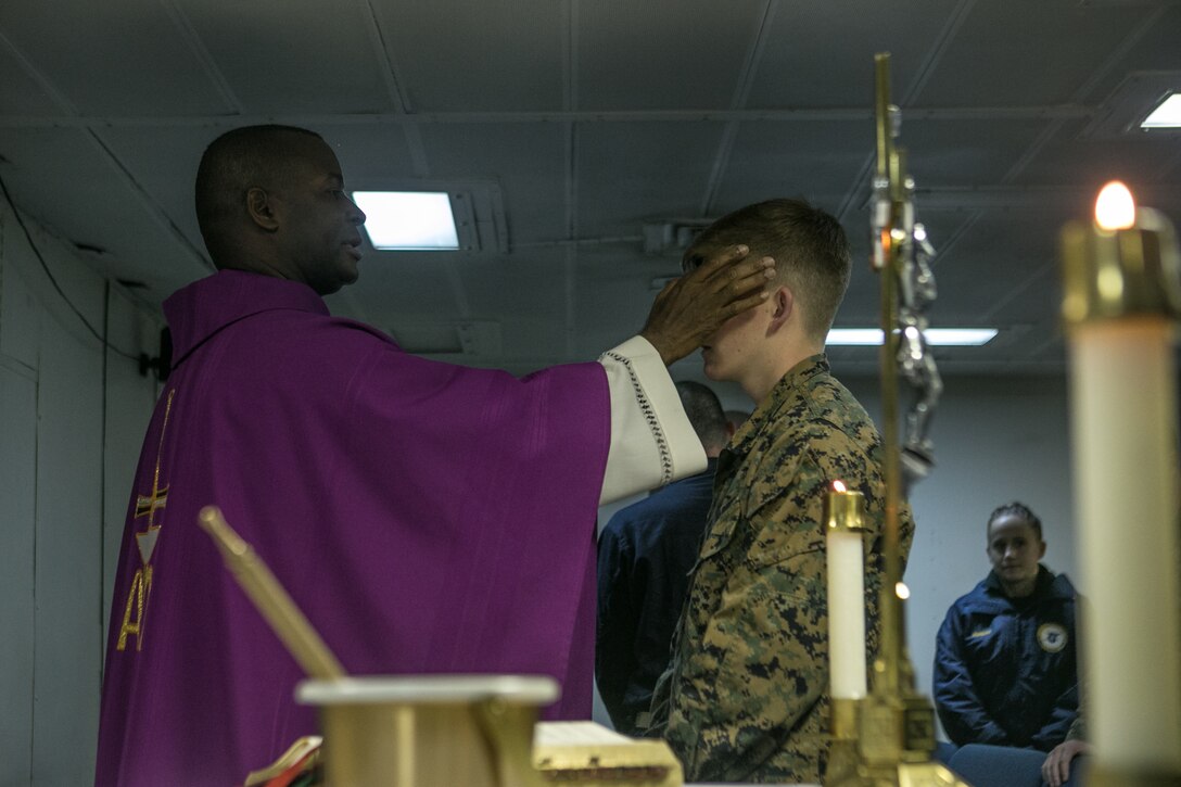 U.S. Navy Lt. Donelson Thevenin, the chaplain of Battalion Landing Team, 2nd Battalion, 6th Marine Regiment (BLT 2/6), 26th Marine Expeditionary Unit (MEU), places ash on the forehead of a Marine with the 26th MEU during an Ash Wednesday service aboard the amphibious assault ship USS Iwo Jima (LHD 7), Feb. 14, 2018.