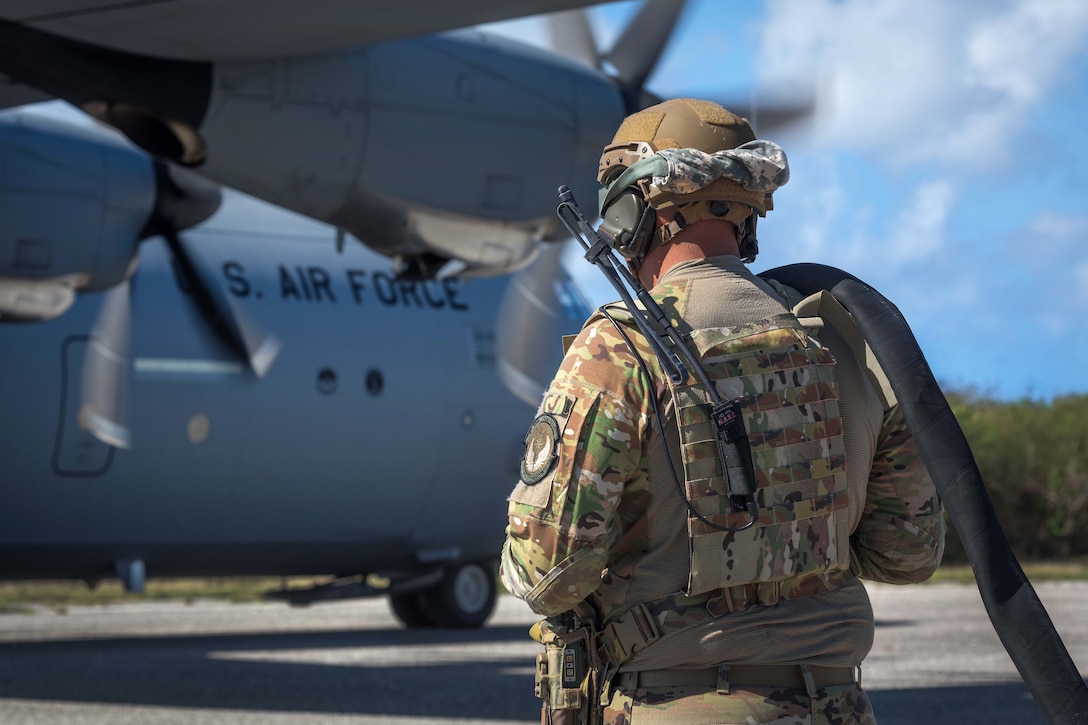 An airman prepares to connect a helicopter expedient refueling system to a C-130J Super Hercules.