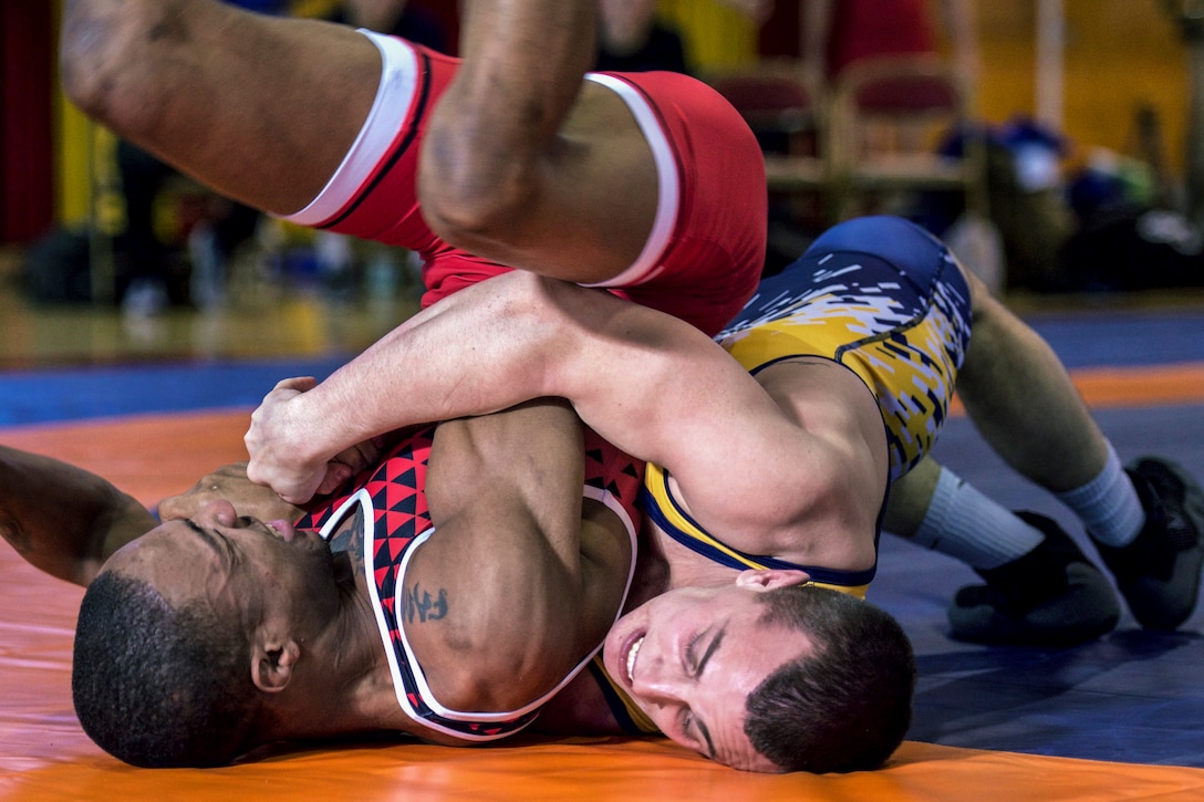 A wrestler drives his opponent into the mat during a competition.