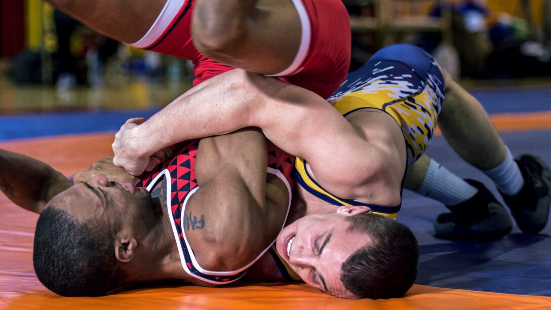 A wrestler drives his opponent into the mat during a competition.