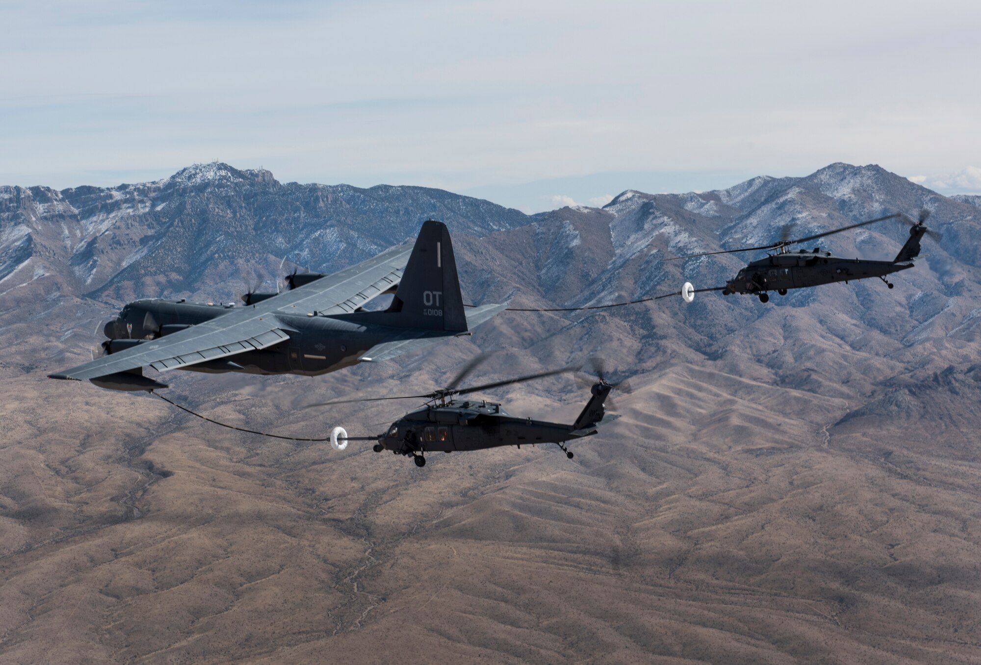 A pair of HH-60 Pave Hawk helicopters receive fuel from a HC-130J Combat King II during a training mission over the Nevada Test and Training Range Feb. 22, 2018. The HC-130J is designed to conduct personnel recovery missions, provide a command and control platform, in-flight refuel helicopters, and carry supplemental fuel for extending range or air refueling. (U.S. Air Force photo by Senior Airman Kevin Tanenbaum)