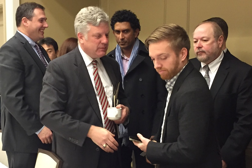 A man speaks to a reporter while surrounded by others.