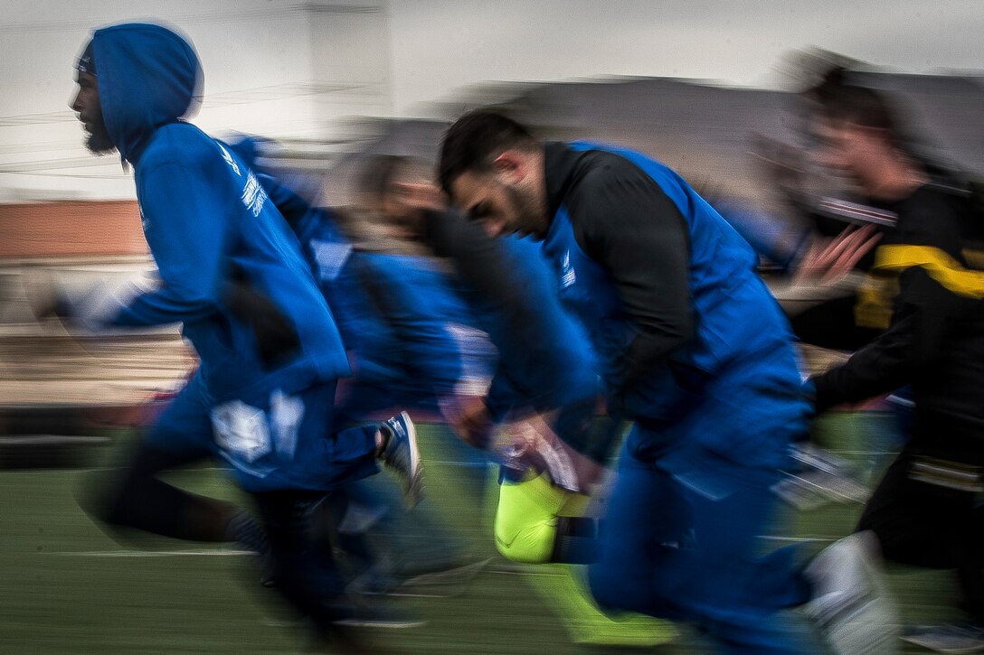 Airmen in blue athletic gear warm up before a sprint track event.