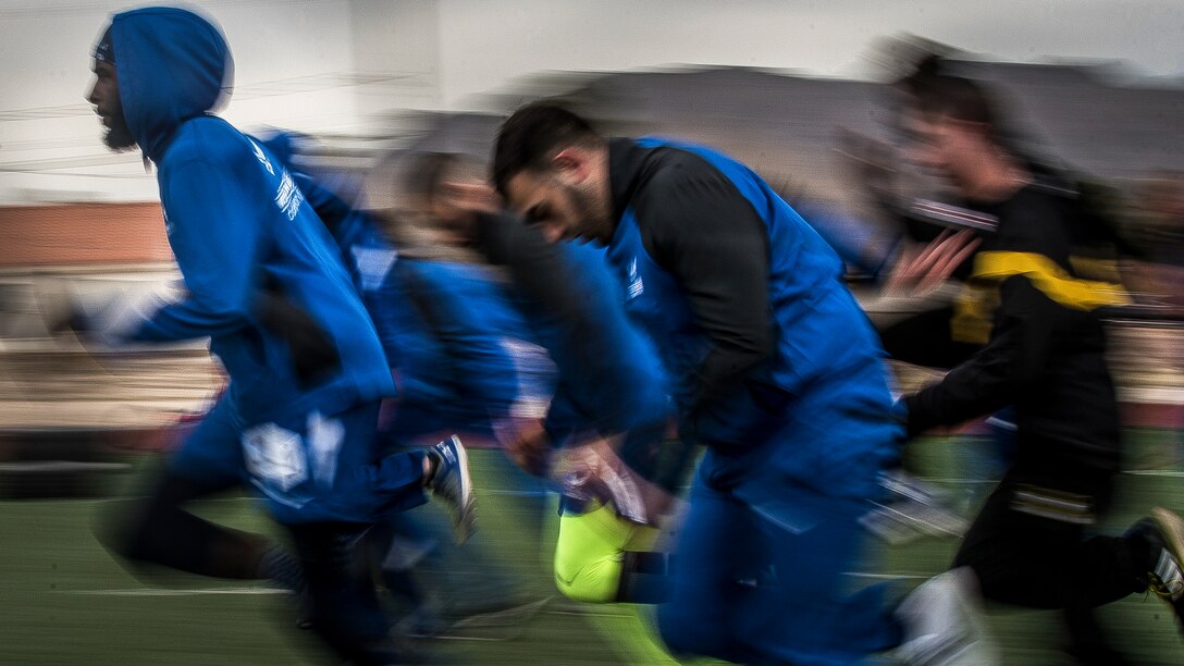 Airmen in blue athletic gear warm up before a sprint track event.