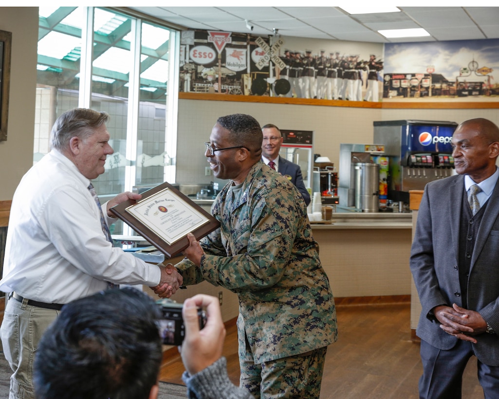Francis Villeme, personal and professional development program manager, receives a certificate of appreciation from Col. Sekou Karega, base commander, during his retirement luncheon in the Route 66 Café aboard Marine Corps Logistics Base Barstow, Calif., Feb. 22.