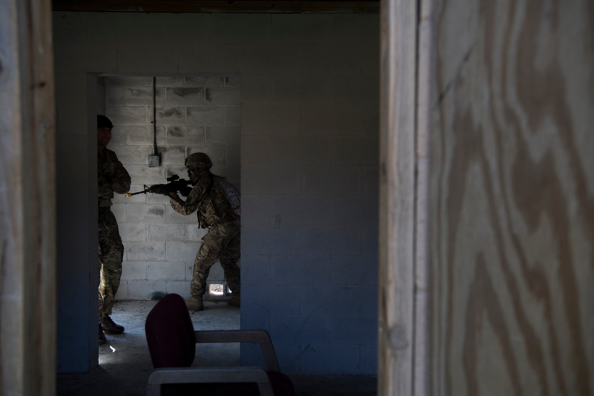 An Airman from the 824th Base Defense Squadron guards the entrance to a building while British Royal Air Force Sgt. Glenn Risebrow, left, 15th Squadron senior noncommissioned officer in charge of training, observes during close-quarters battle training, Feb. 28, 2018, at Moody Air Force Base, Ga. The 820th Base Defense Group welcomed a member of the British Royal Air Force to embed into multiple training situations to help strengthen combined operations between U.S. and British forces. (U.S. Air Force photo by Senior Airman Daniel Snider)